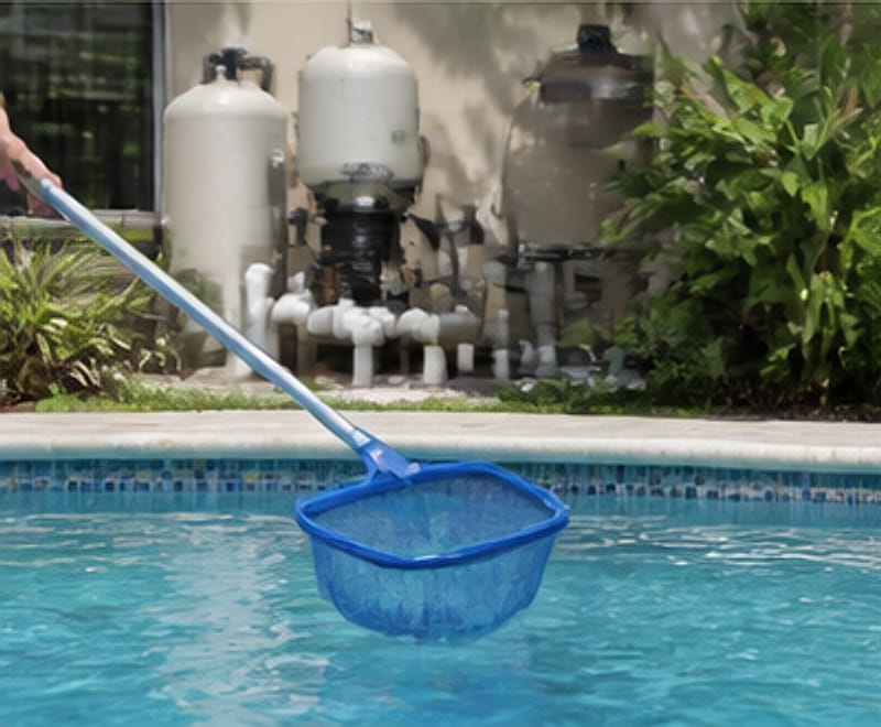 Technician skimming a pool in front of a filter and pump equipment pad.