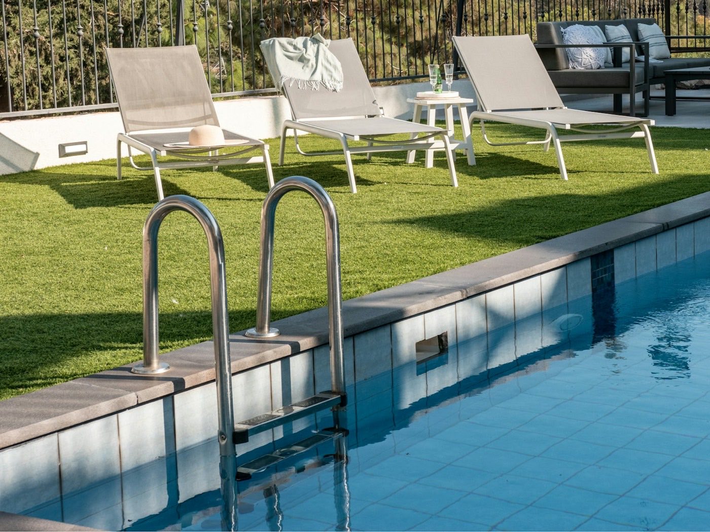 Lounge chairs lined along a pool deck on a bright afternoon.