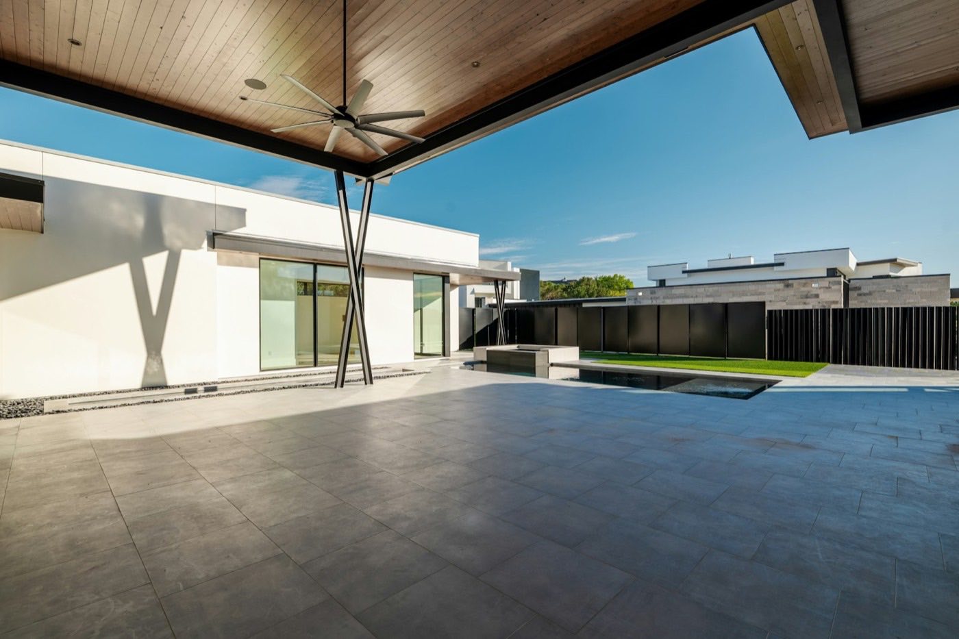 Long modern pool running alongside a covered patio.