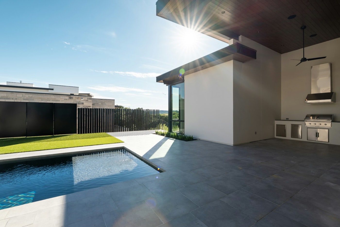 Poolside patio with a built-in outdoor kitchen and bar seating.