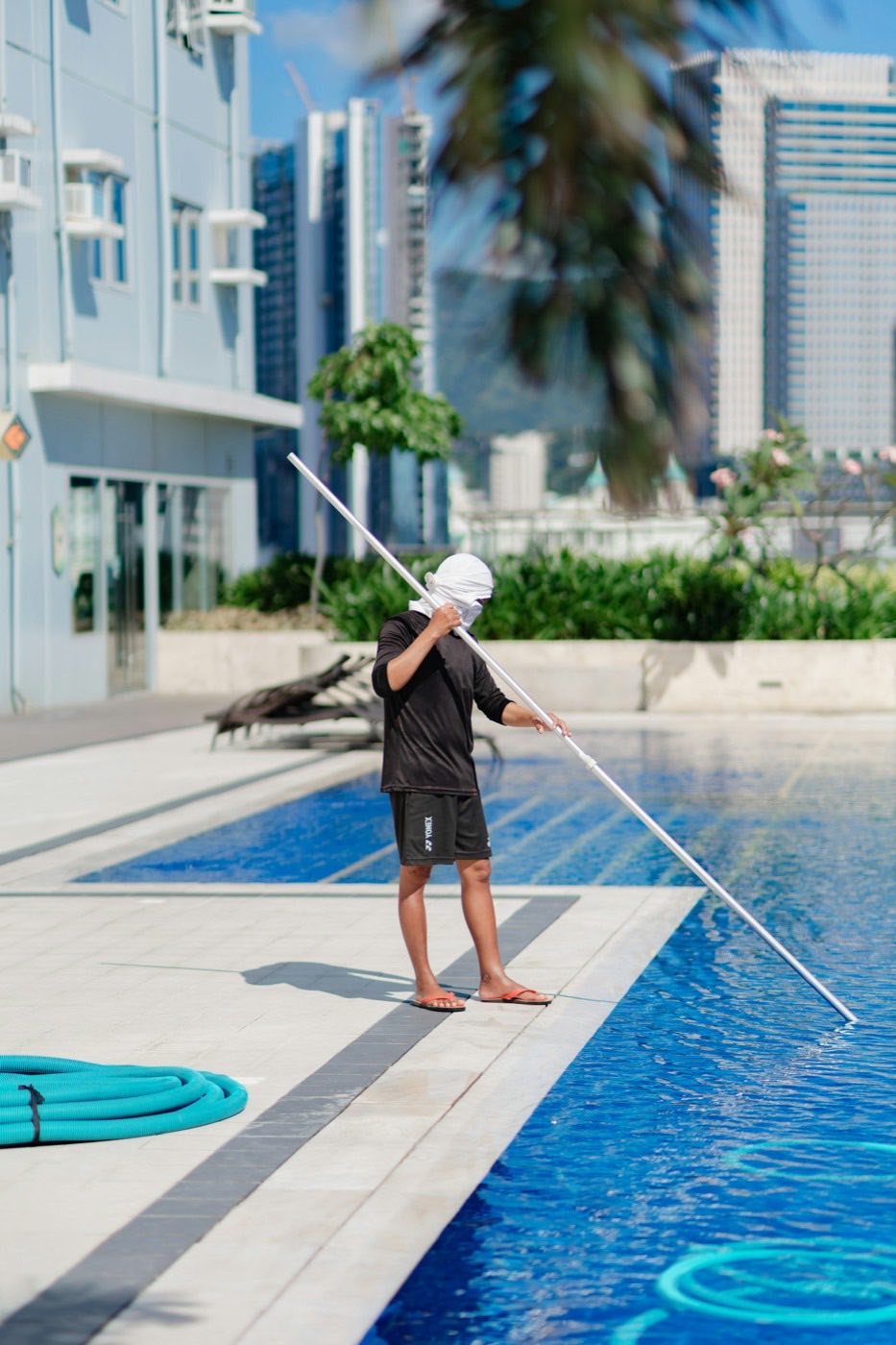 Service technician skimming a pool with a long-handled net.