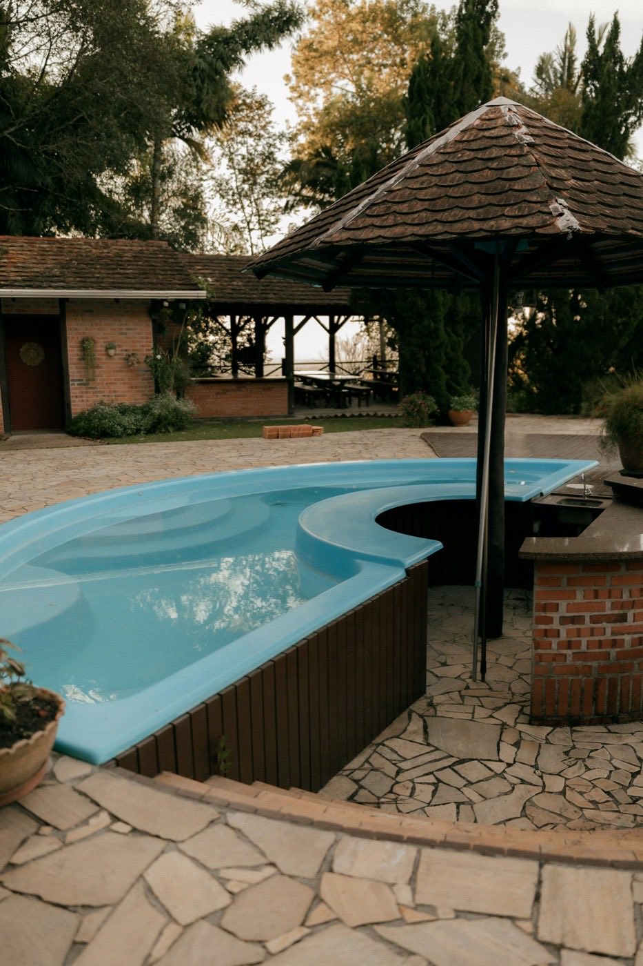 Curved pool with a raised wall and a shaded swim-up seating area.